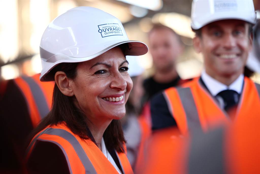 巴黎市長伊達戈（Anne Hidalgo）的民調支持率並不出色，仍獲提名代表社會黨參加2022年總統大選。圖為她與法國總統馬克宏（後者），配戴工地帽參觀奧運選手村建築工地。